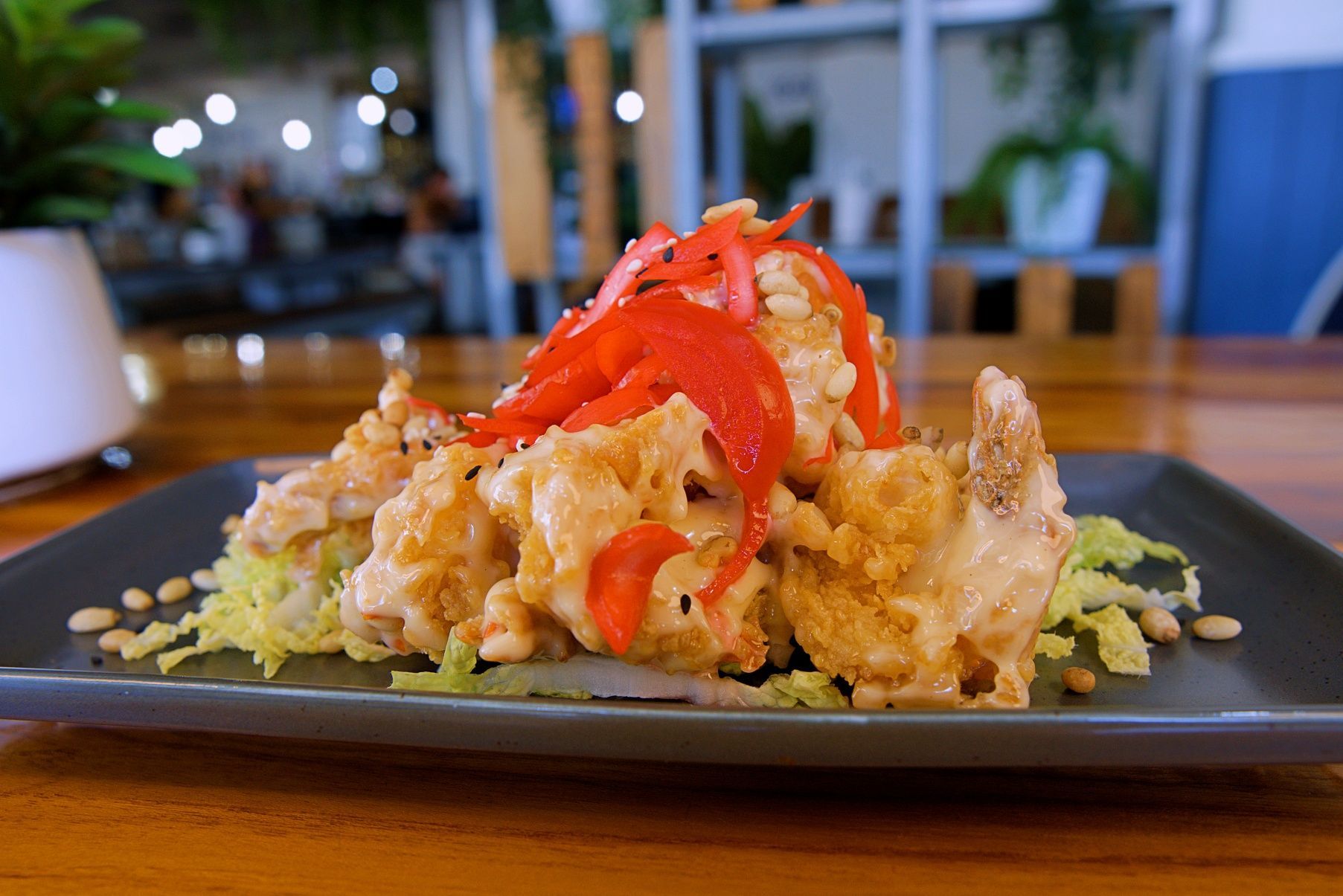 Crispy Fried Food With Sauce and Red Peppers on a Bed of Greens, Served on a Gray Plate — Chop 'n Chill in Port Macquarie, NSW