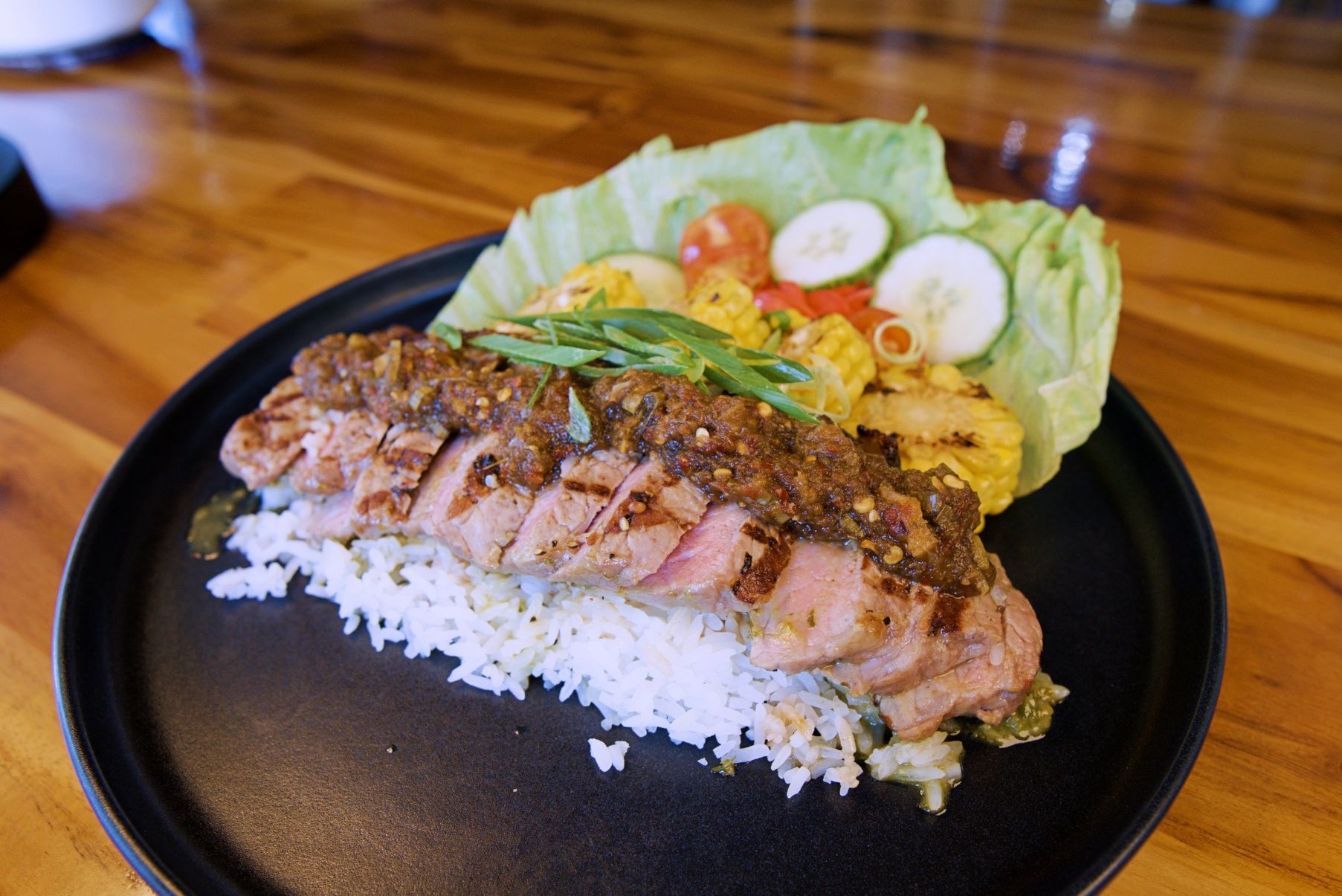 Grilled Meat With Sauce Over Rice, Corn, and Vegetables on a Black Plate — Chop 'n Chill in Port Macquarie, NSW