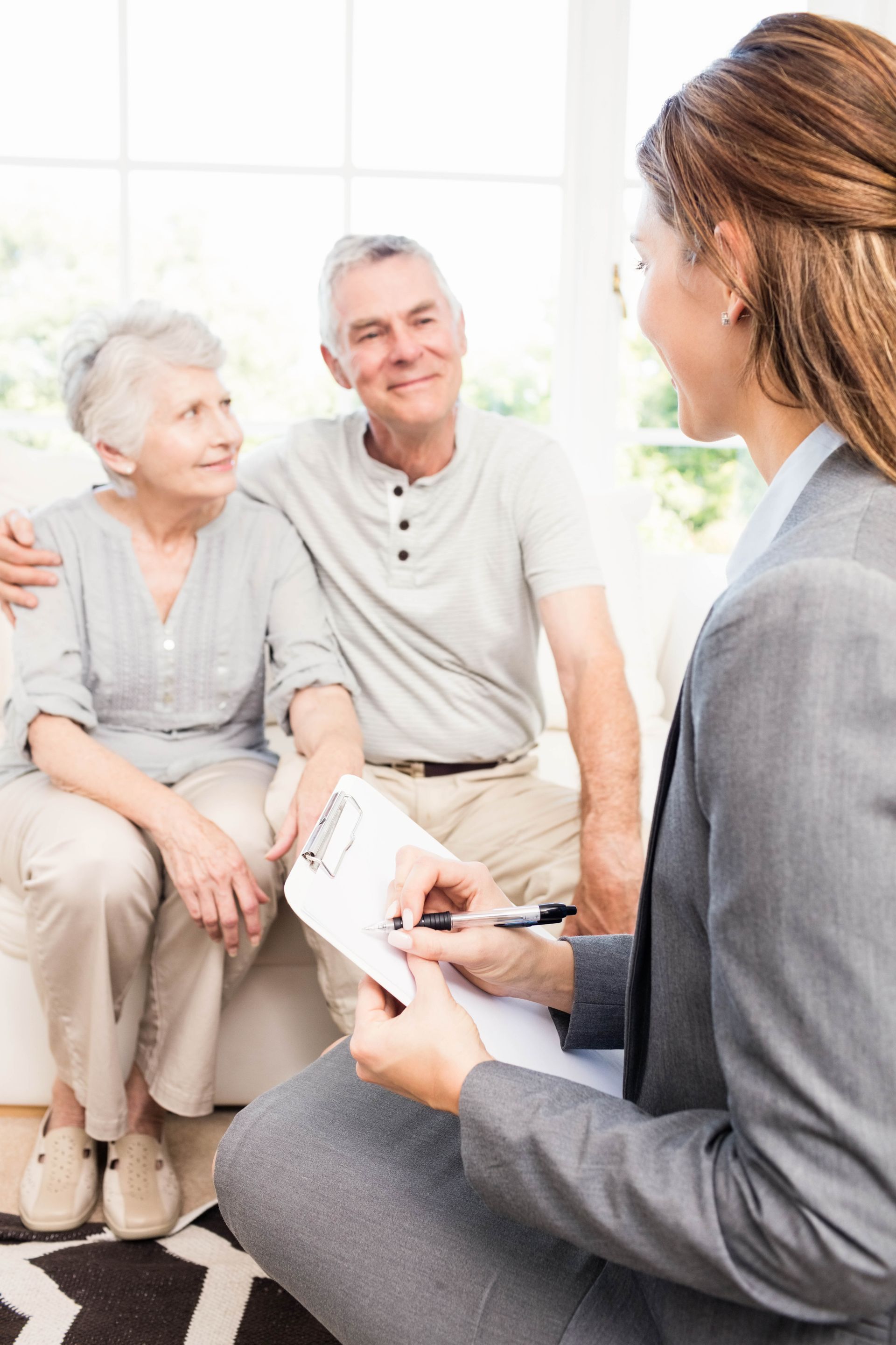 Couple reviewing a document with a person, indoors. They smile, looking at the person who is holding the document.