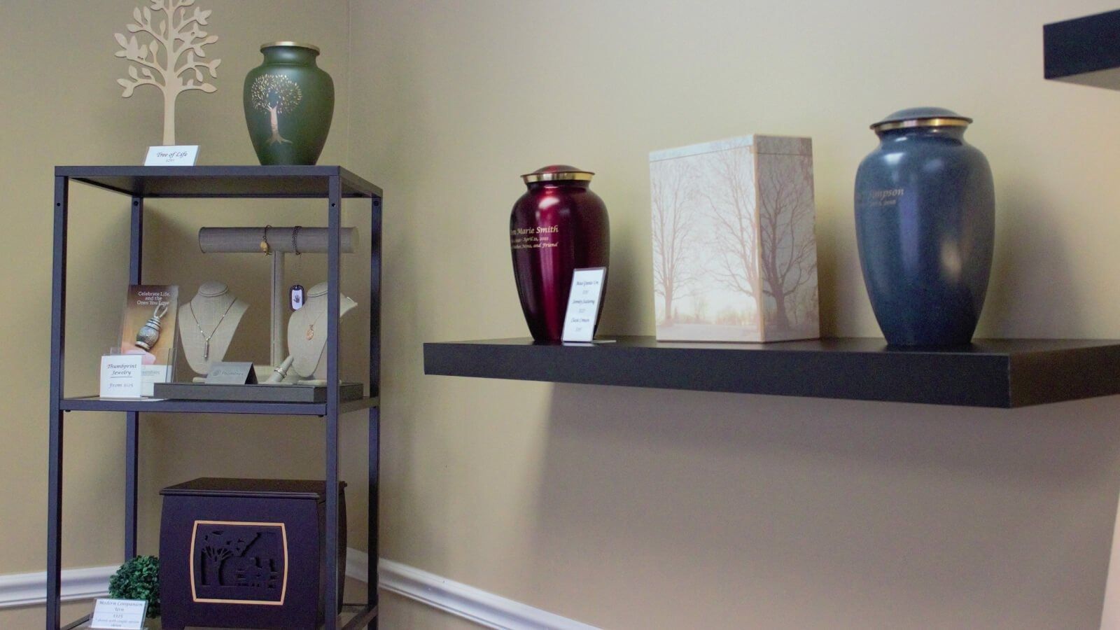 Decorative vases and a lamp on black shelves against a beige wall