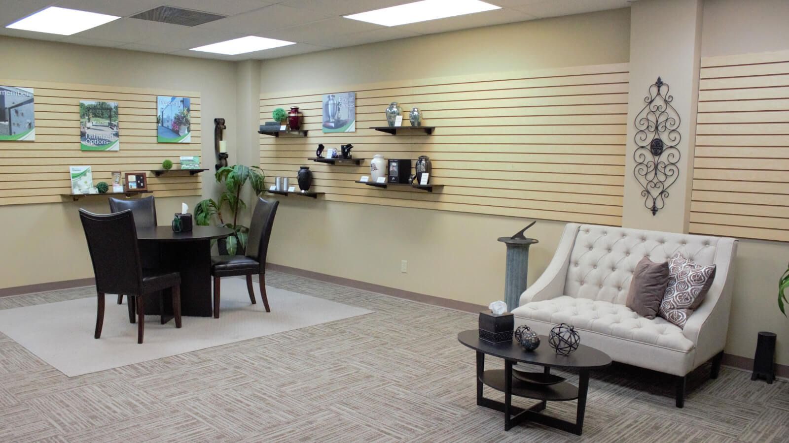 Showroom with beige walls, display shelves, a small dining table, and a white sofa with black side table.