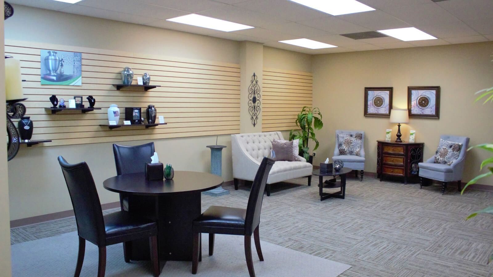 Bright office lounge with round table, chairs, sofa, and wall shelves displaying products and decor