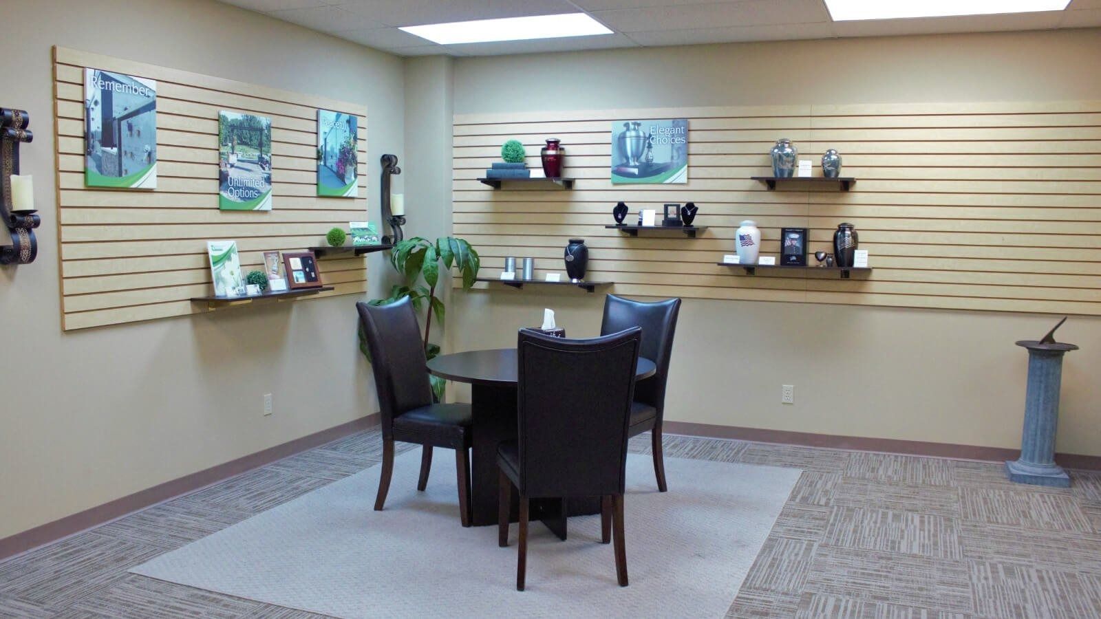 Small office waiting area with chairs, table, wall shelves, and framed artwork.
