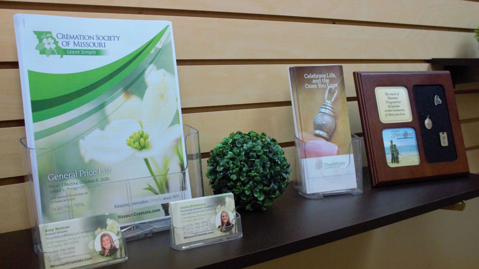 Award display on a shelf with certificates, brochures, a small plant, and framed plaques.
