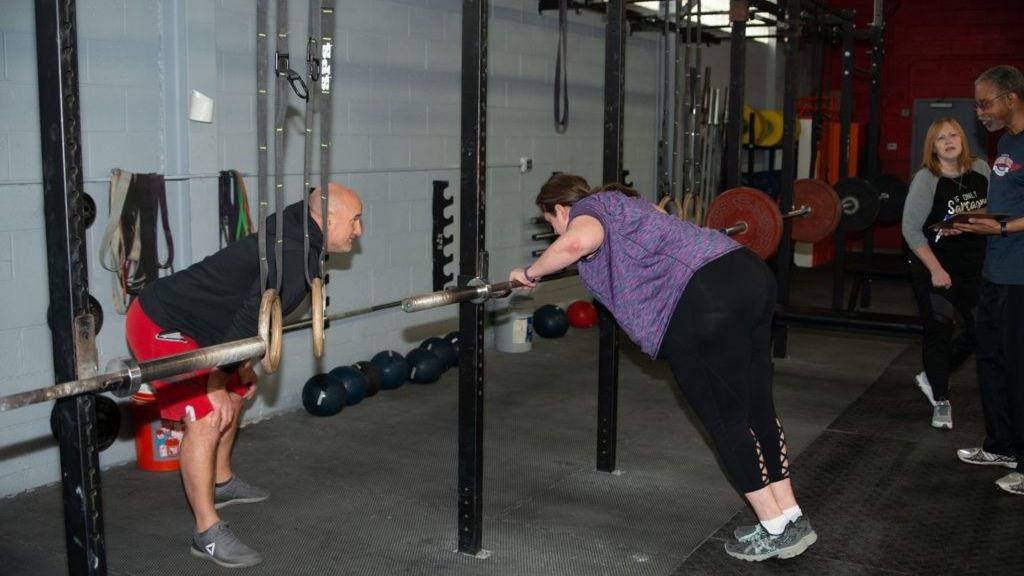 A man and a woman are doing squats in a gym.