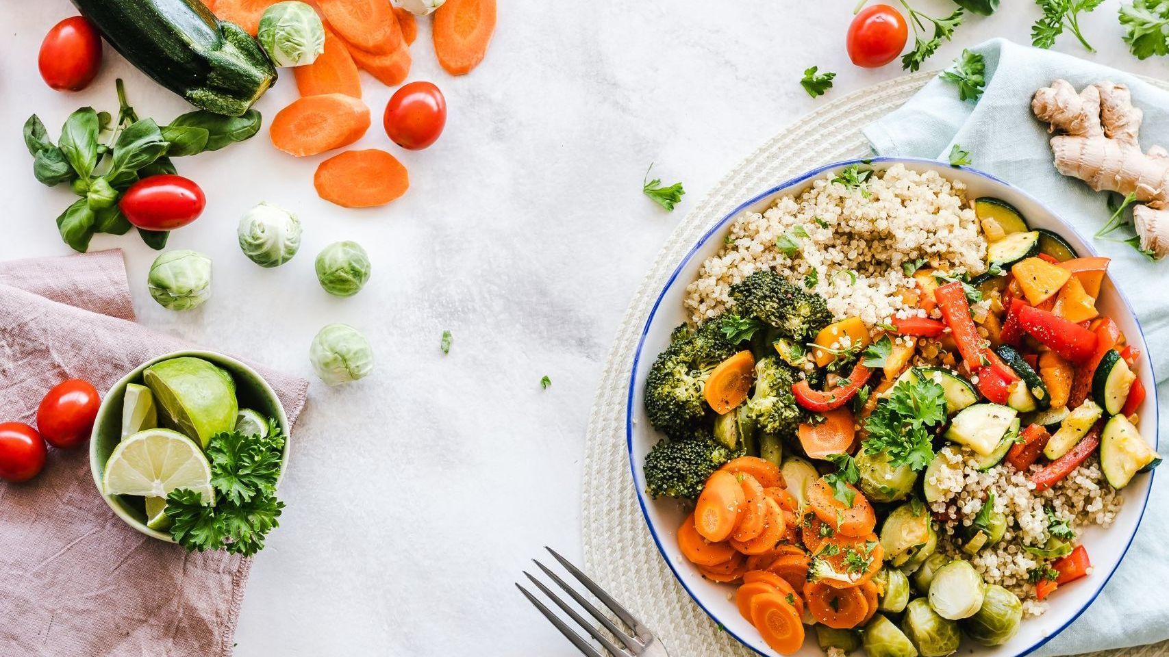 A bowl of vegetables and rice on a table with a fork.