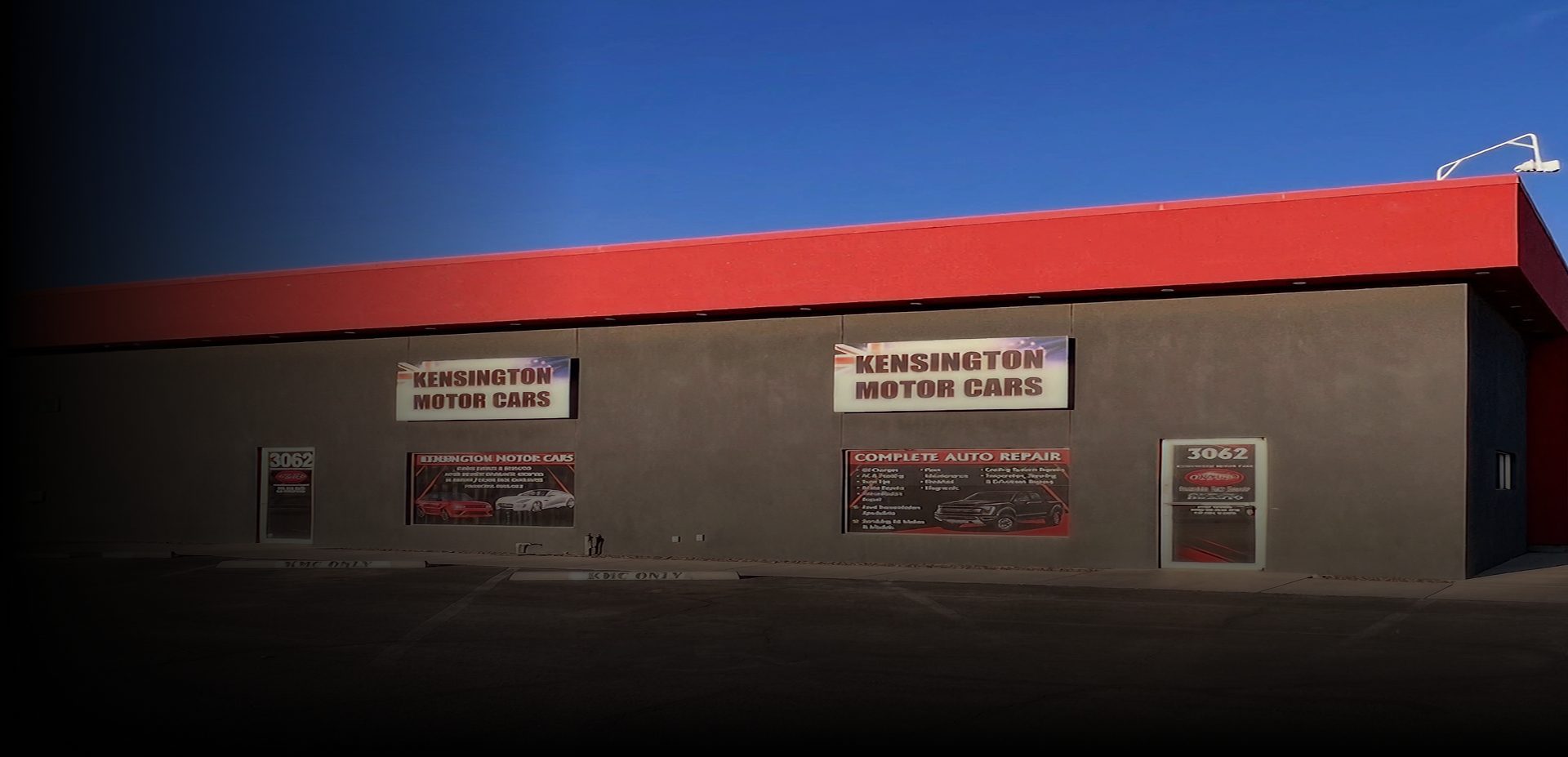 A wide view of a grey commercial building with a bright red roof and 