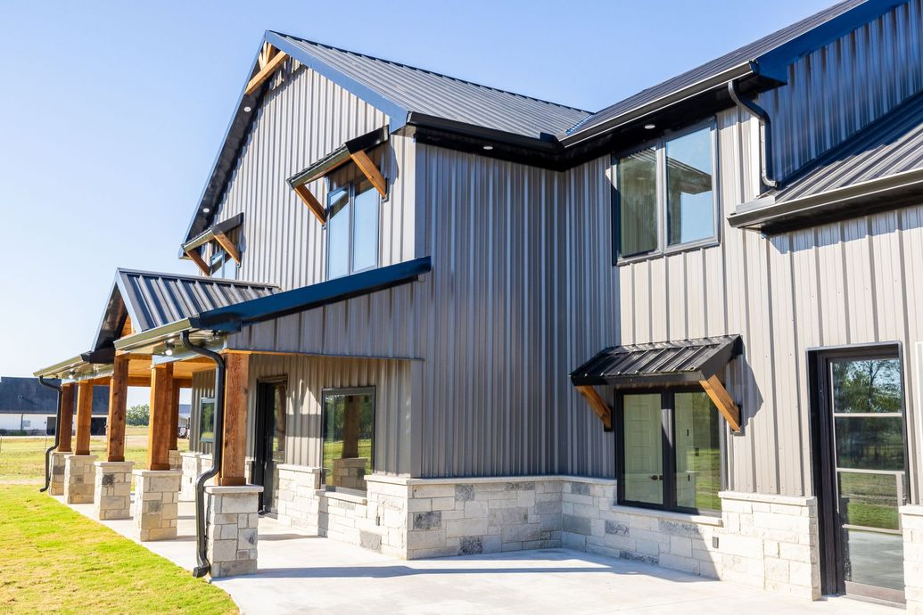 A large gray house with a black roof and a lot of windows.