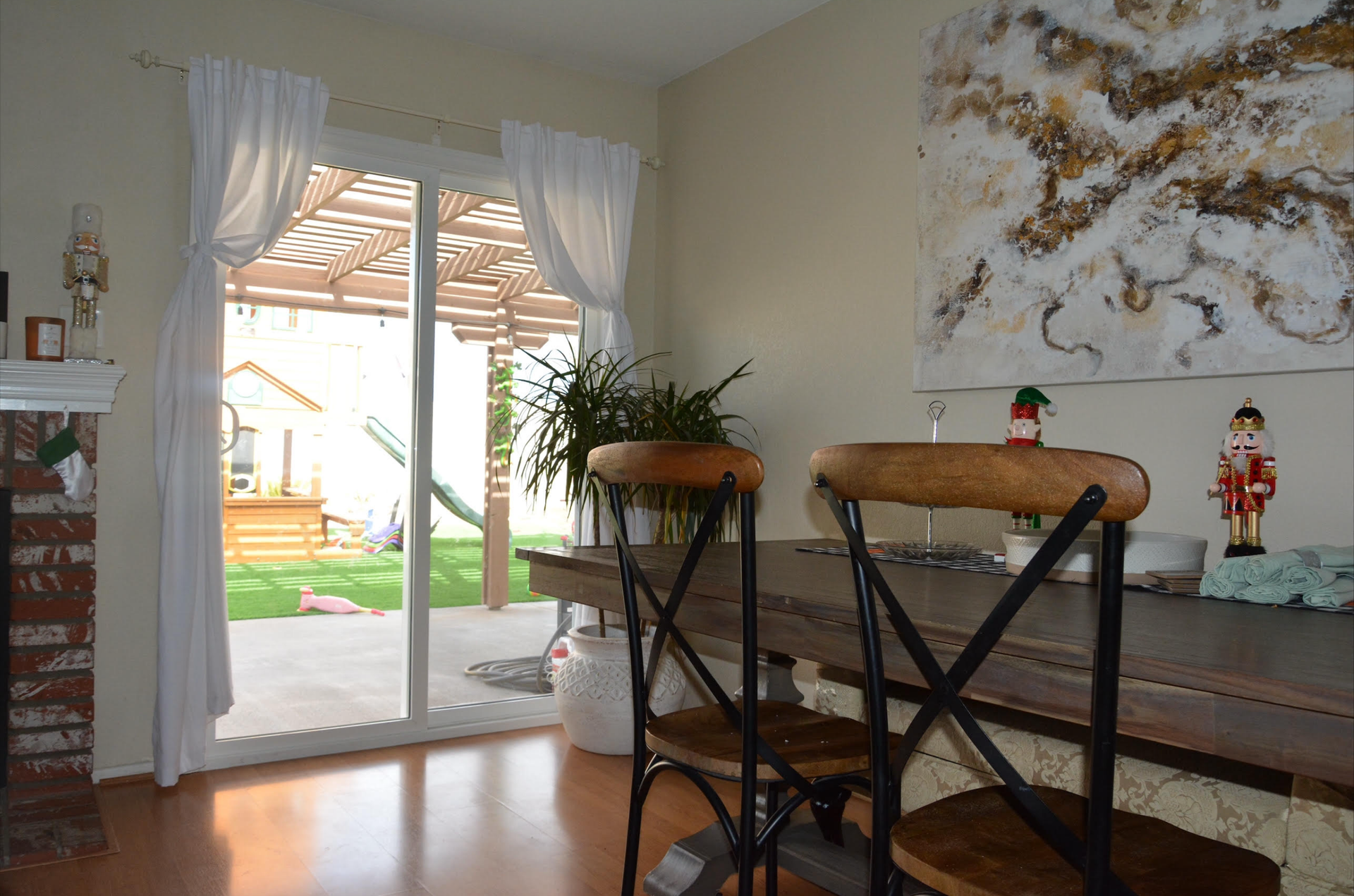 Dining room with table, chairs, sliding door to backyard, artwork, and curtains.