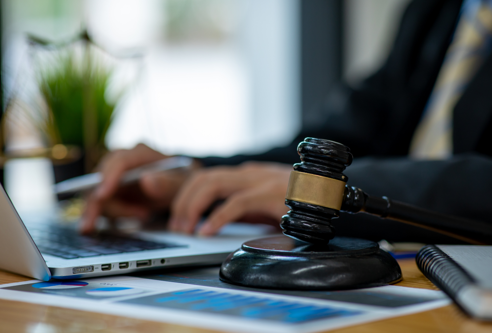 A judge 's gavel is sitting on a table next to a person using a laptop computer.