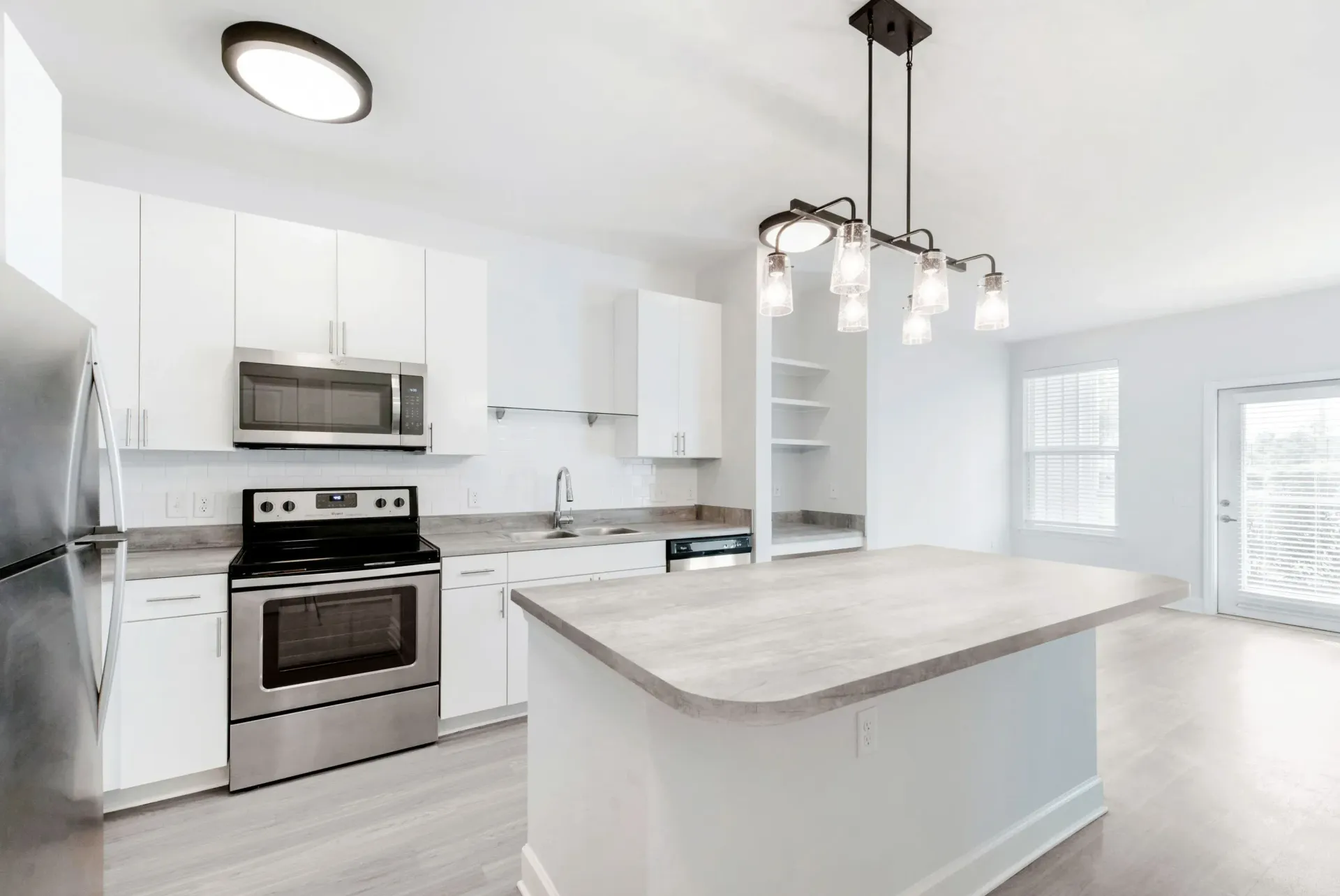 Open-concept kitchen with white cabinetry, stainless steel appliances, and a large island.