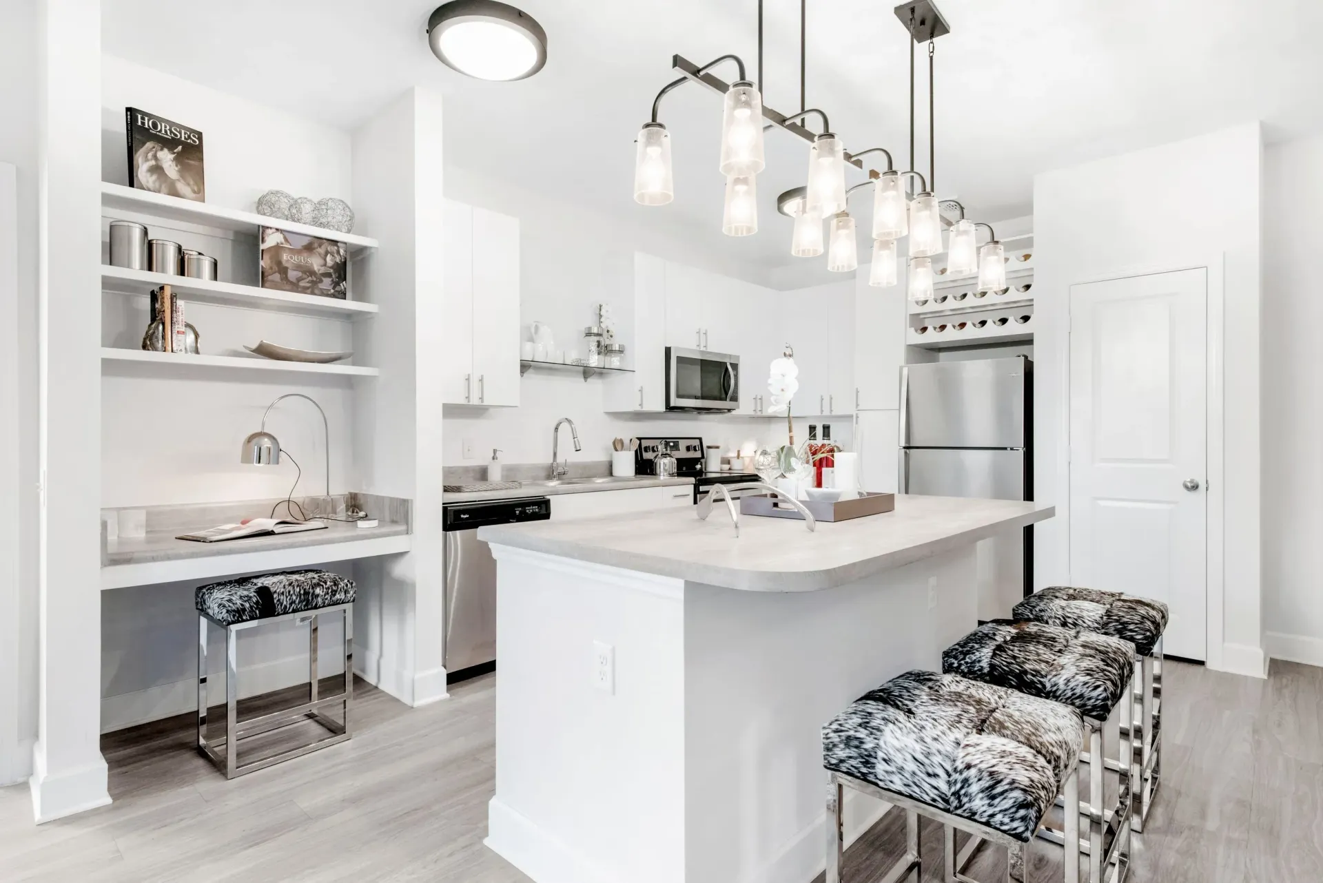 Bright white kitchen with island, pendant lights, and stainless-steel appliances.