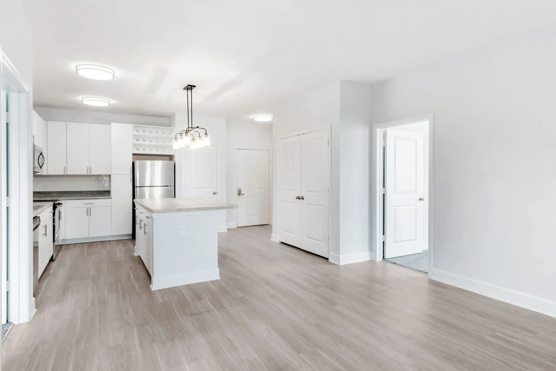 Bright open-concept kitchen with white cabinets, island, and stainless appliances.