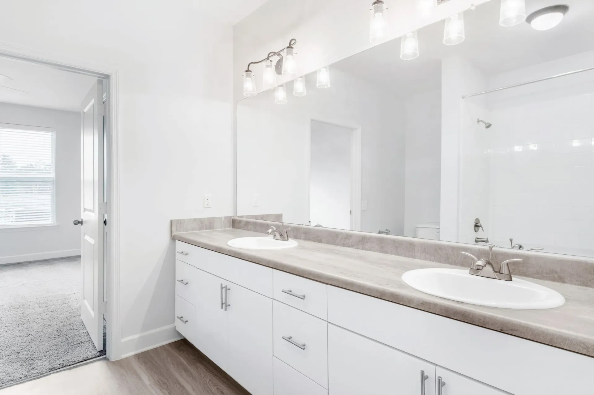 Double-sink bathroom vanity with a large mirror and a tiled shower.