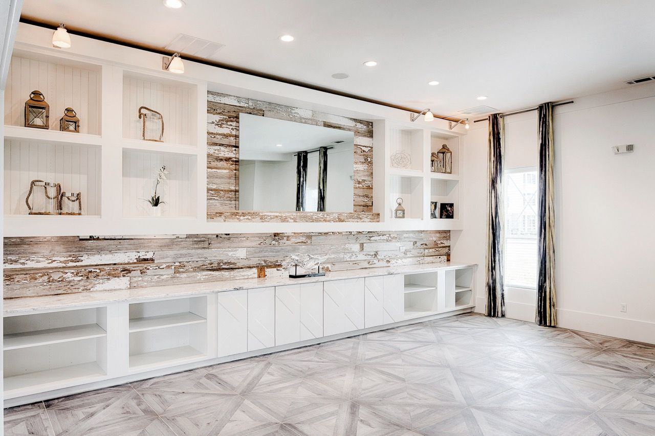 Bright living area with white built-in cabinets and a rustic wood accent wall.