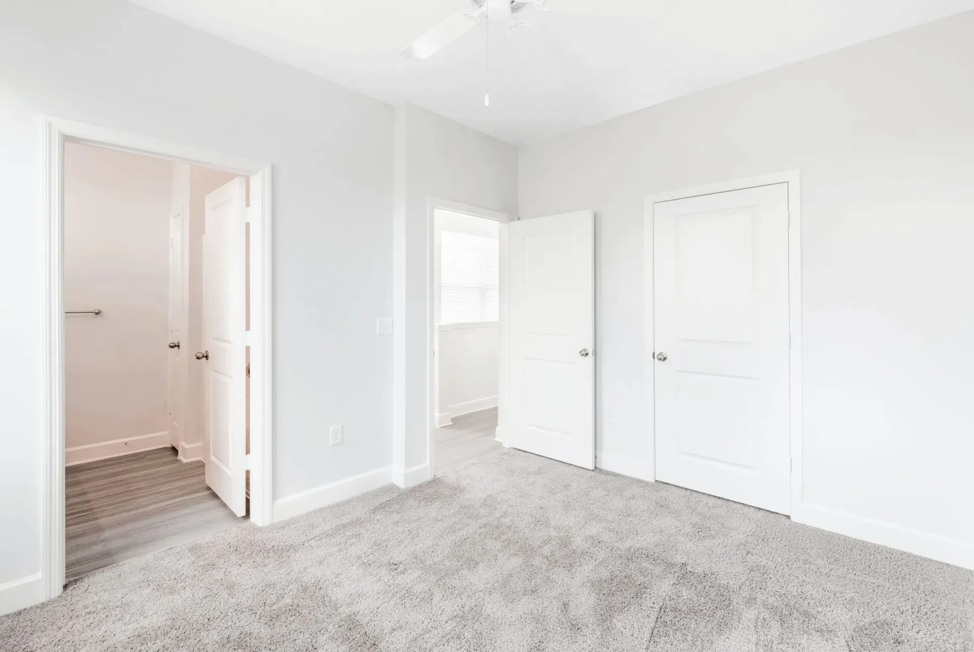 Bright bedroom with light gray walls, white doors, and plush beige carpet.