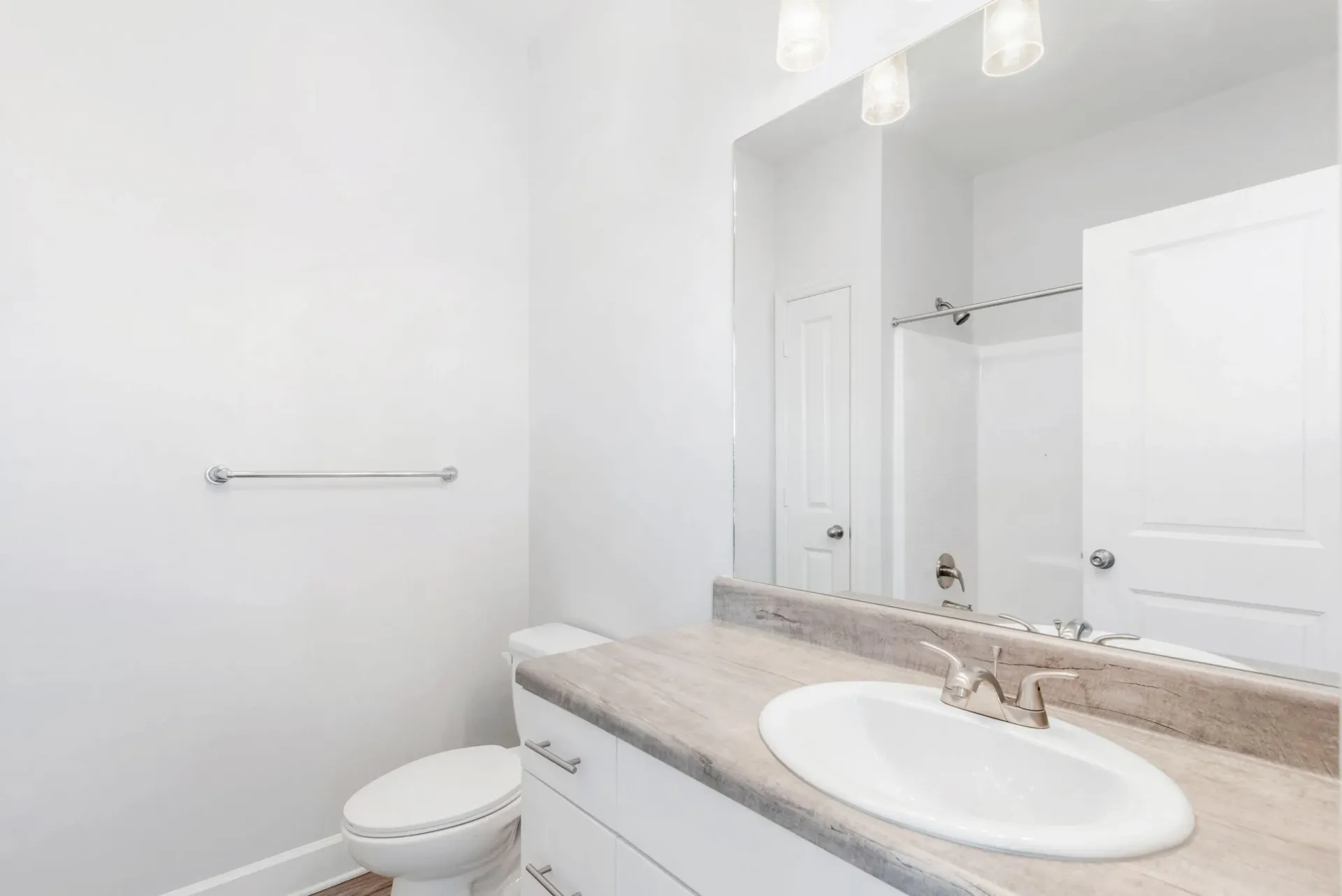 Bright bathroom with white vanity, sink, large mirror, and toilet.