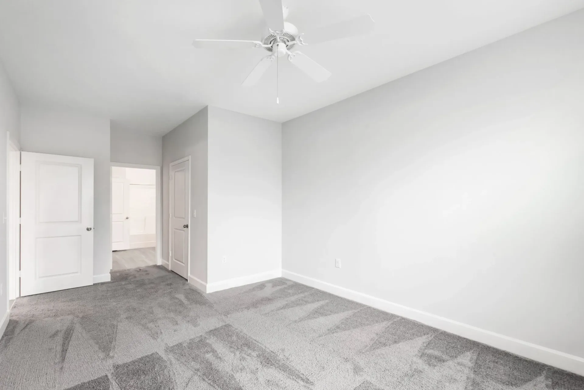 Empty bedroom with gray walls, white trim, and a ceiling fan.