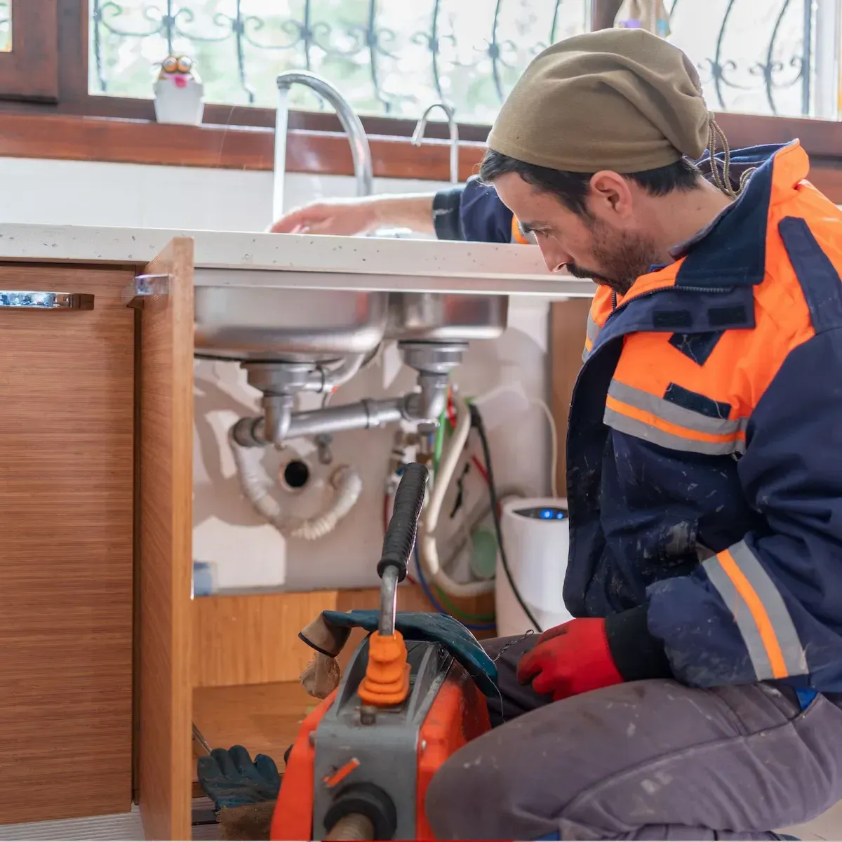 Plumber fixing a clogged kitchen sink in a Commerce City home.