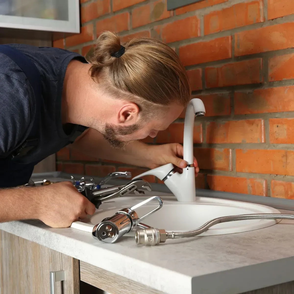 Close-up of plumber’s hands working on faucet replacement in Commerce City.