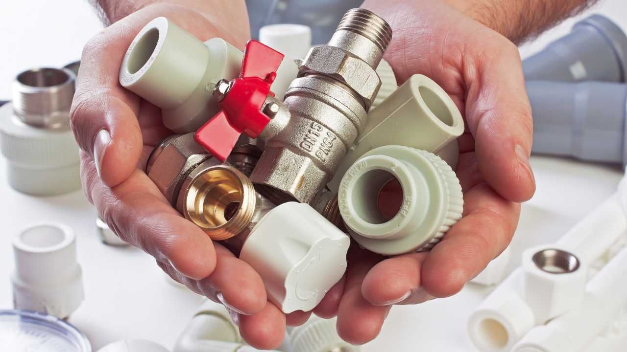 A person displays various plumbing fittings.