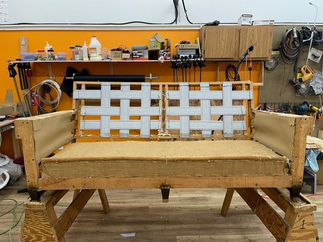 A wooden couch is being built in a workshop