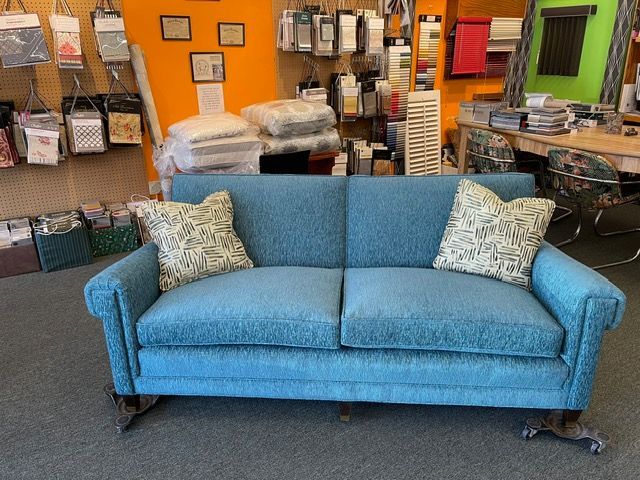 A blue couch with white pillows is sitting in a room.