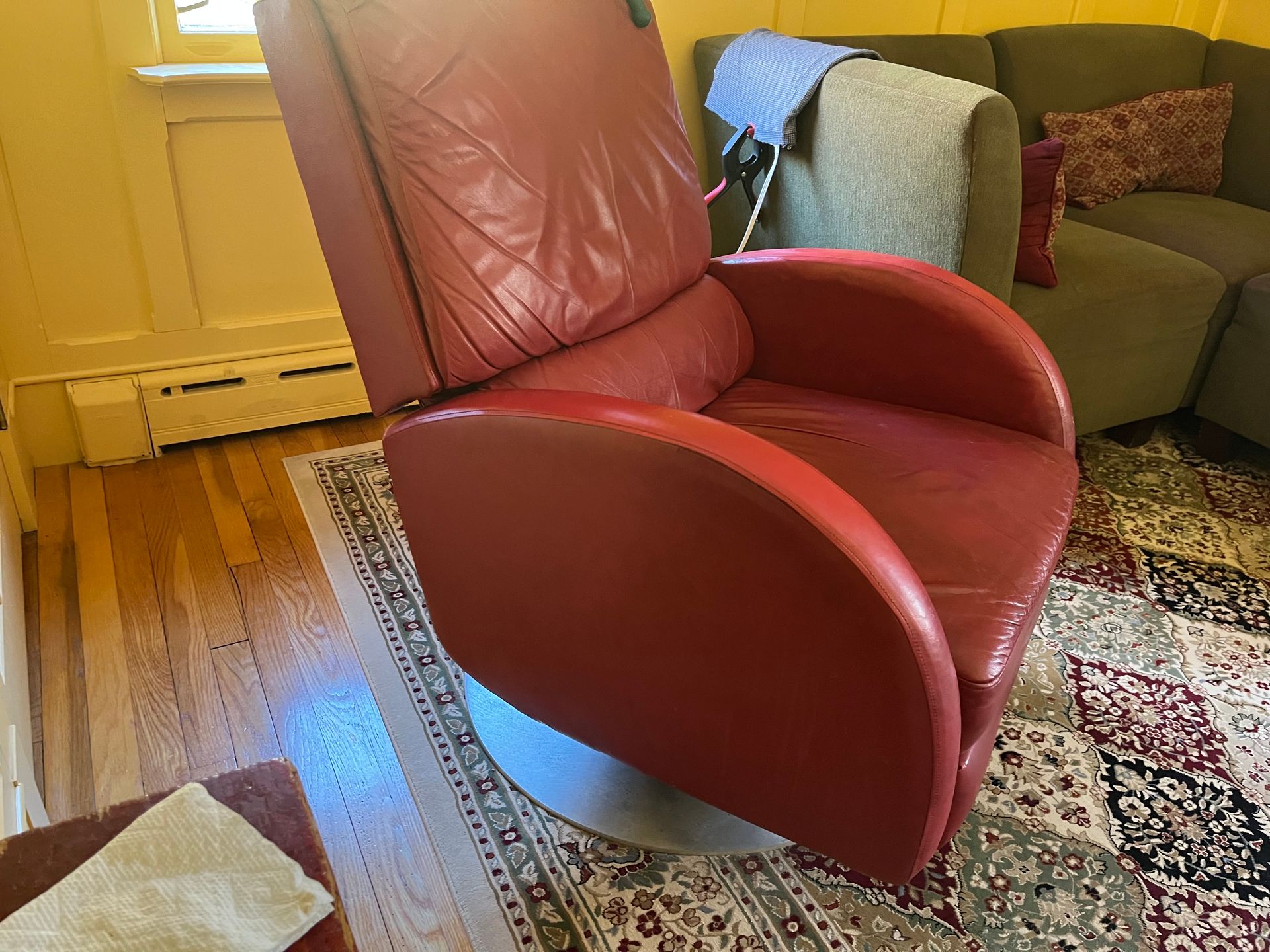 A red leather chair is sitting in a living room next to a couch.