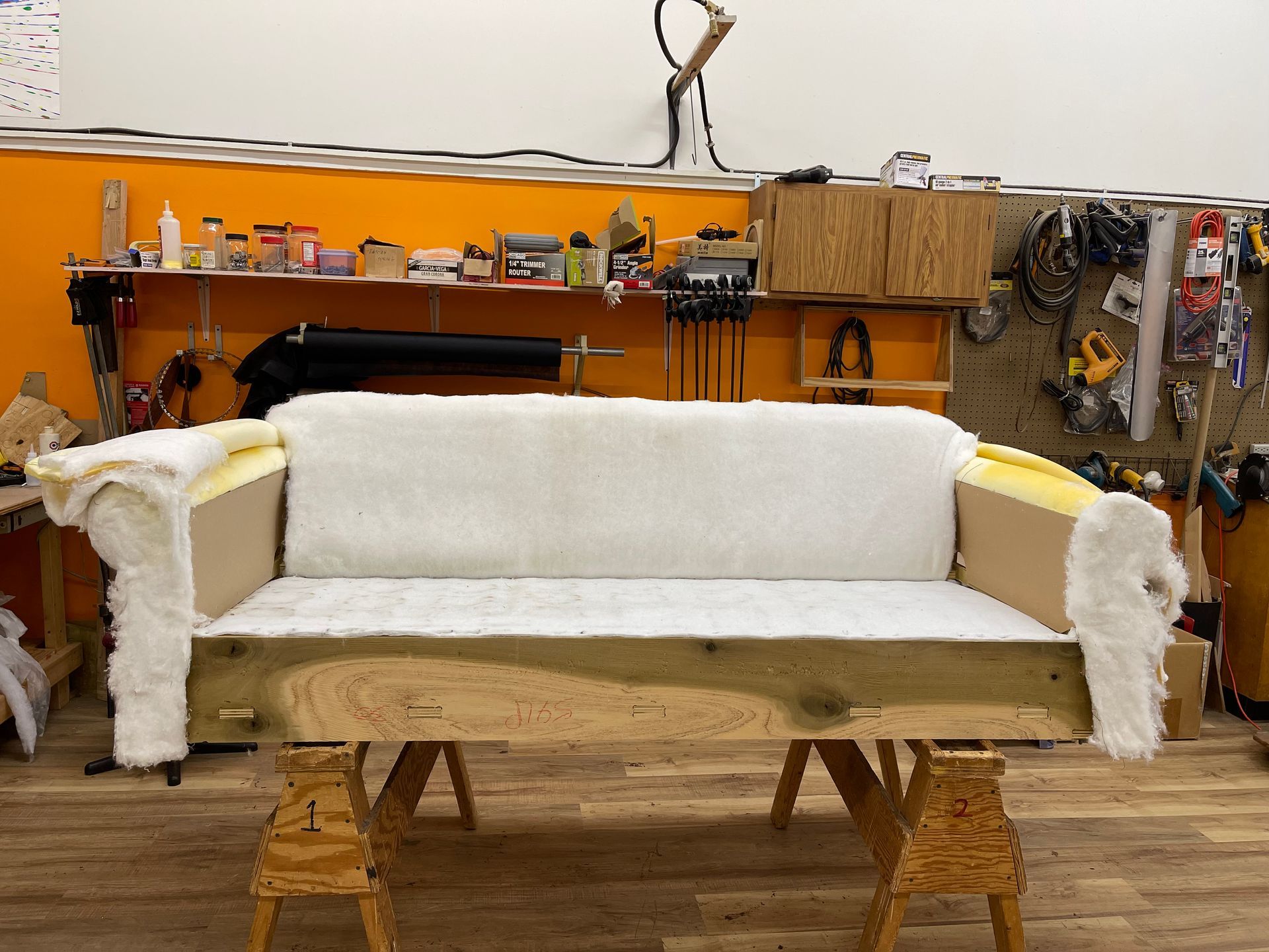 A couch is sitting on a wooden table in a workshop.