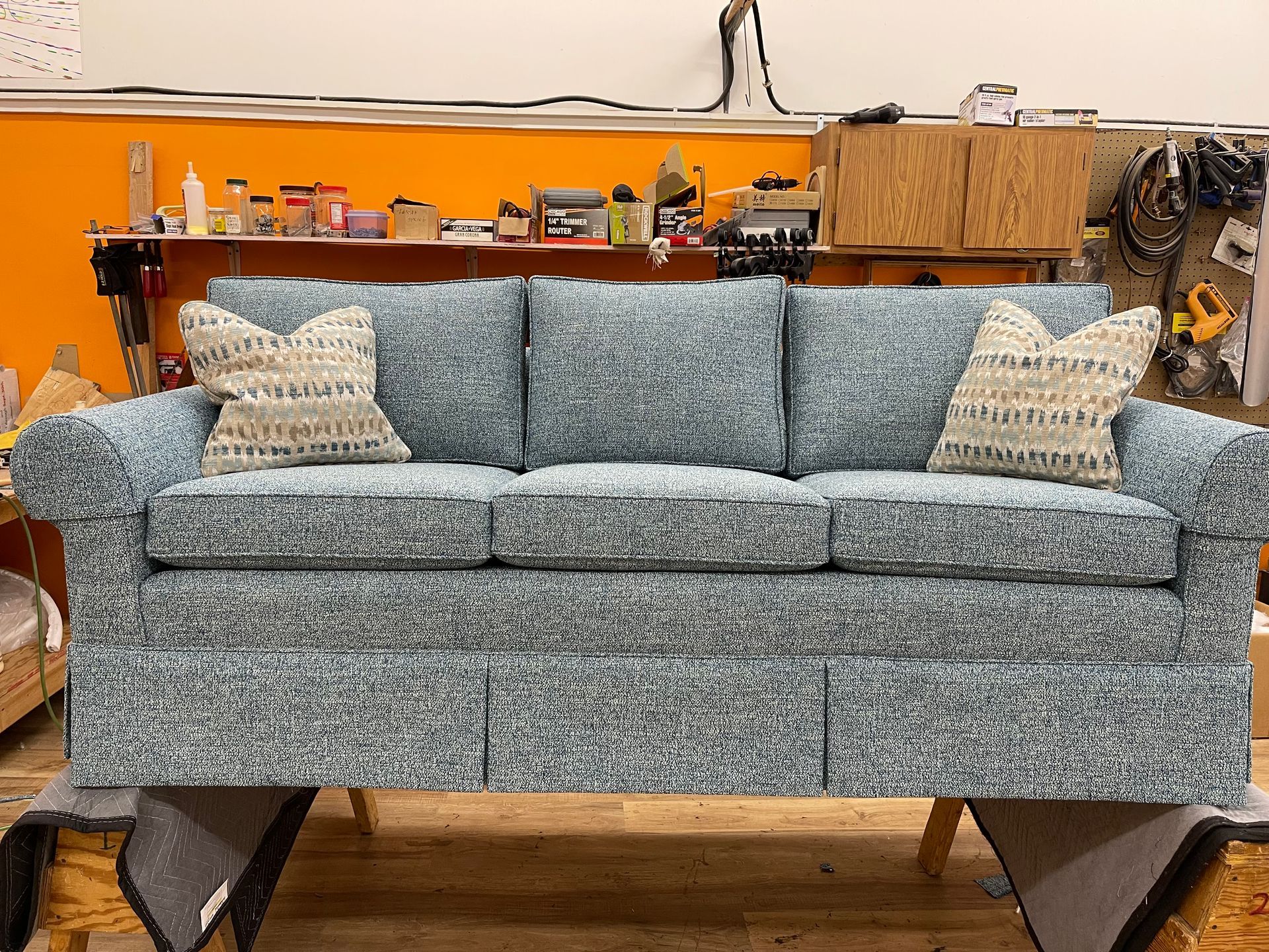 A blue couch is sitting on a wooden table in a room.