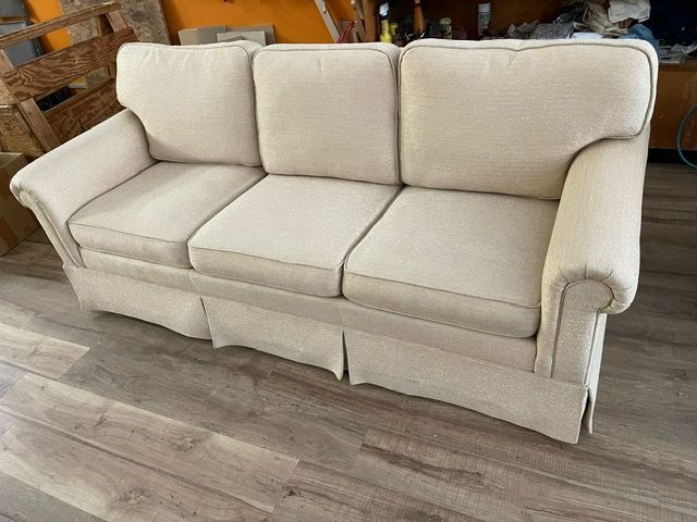 A white couch is sitting on a wooden floor in a living room.