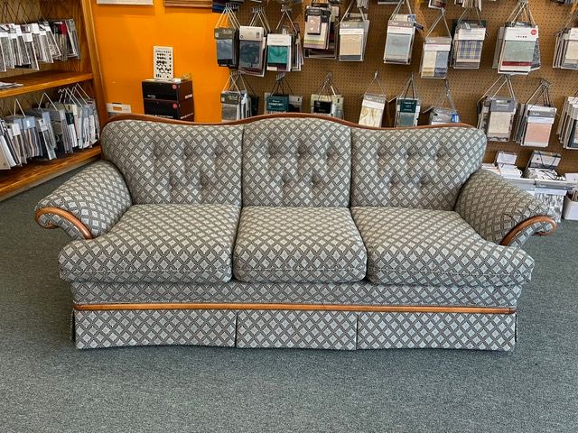 A grey couch is sitting in front of a wall of fabric samples.