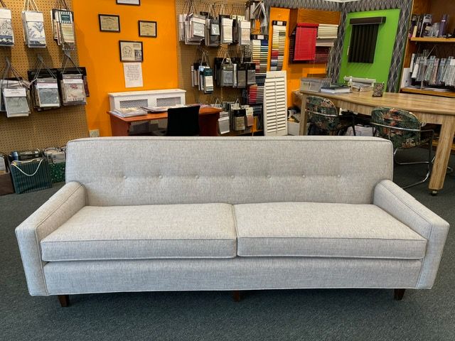A white couch is sitting in a room with a desk in the background