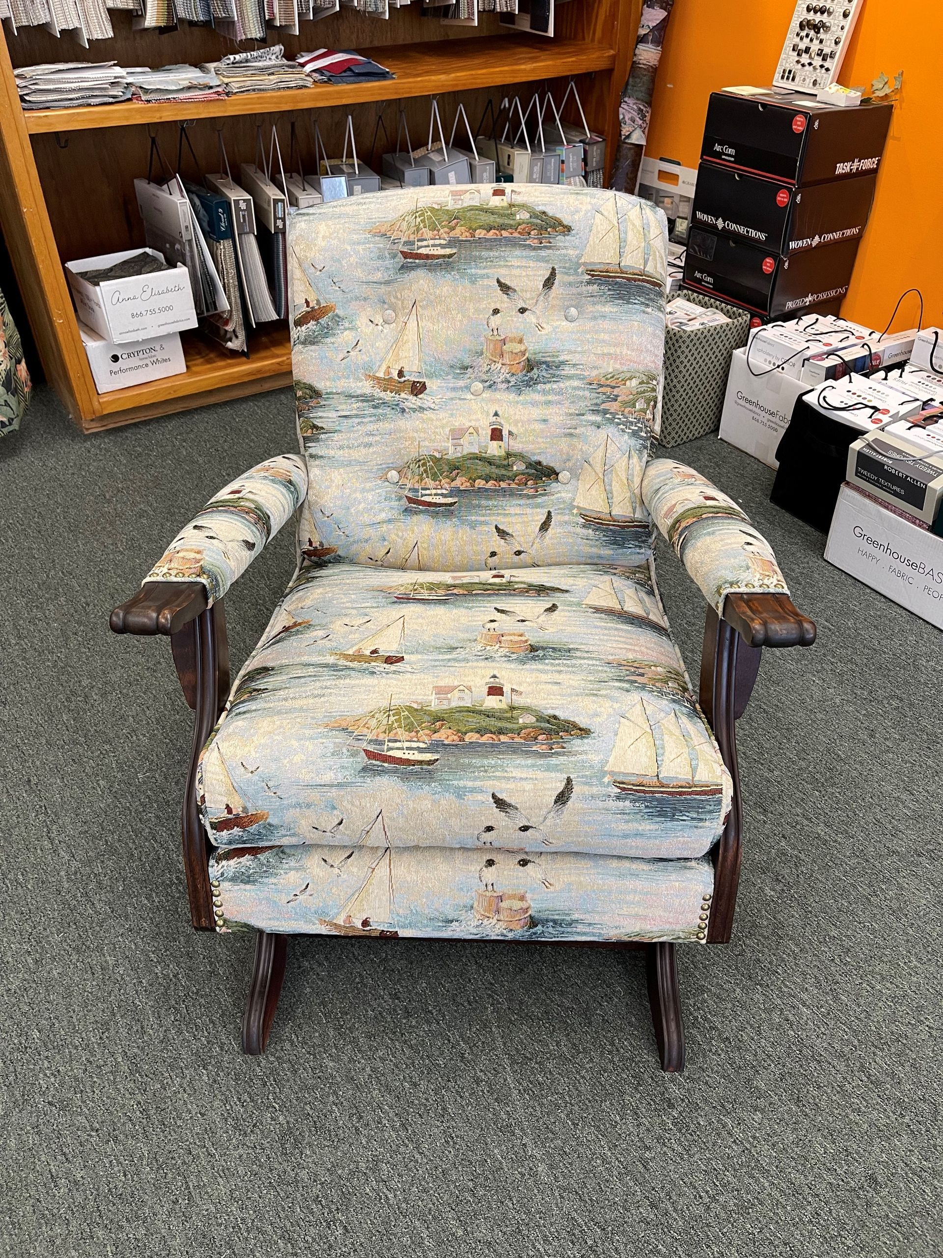 A rocking chair with a sailboat pattern on it is in a room.