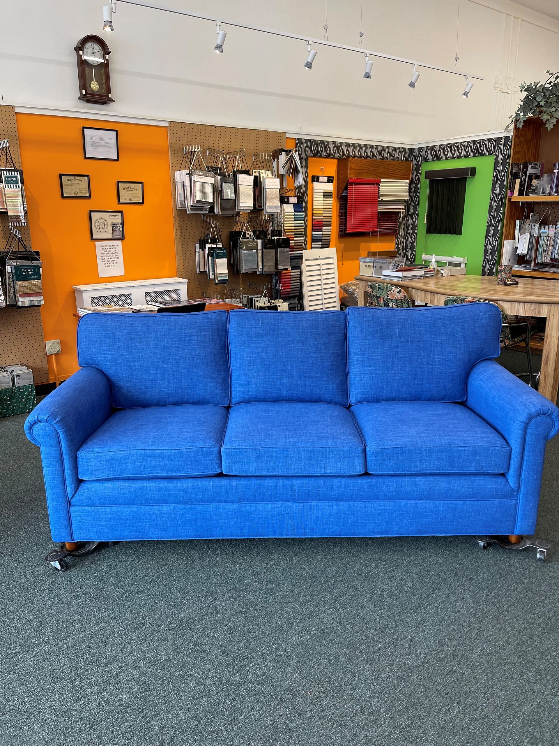 A blue couch is sitting in a room with a clock on the wall.