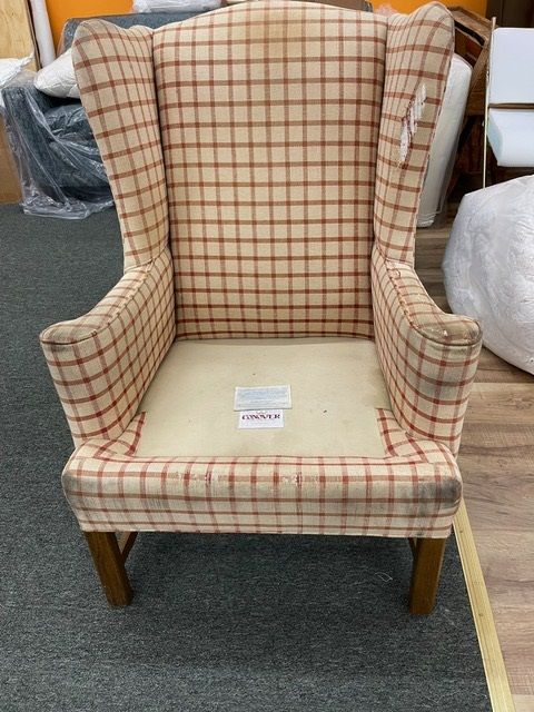 A chair with a plaid pattern is sitting on a carpet in a room.