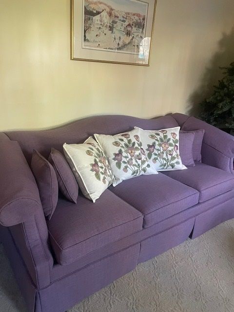 A purple couch with white pillows in a living room
