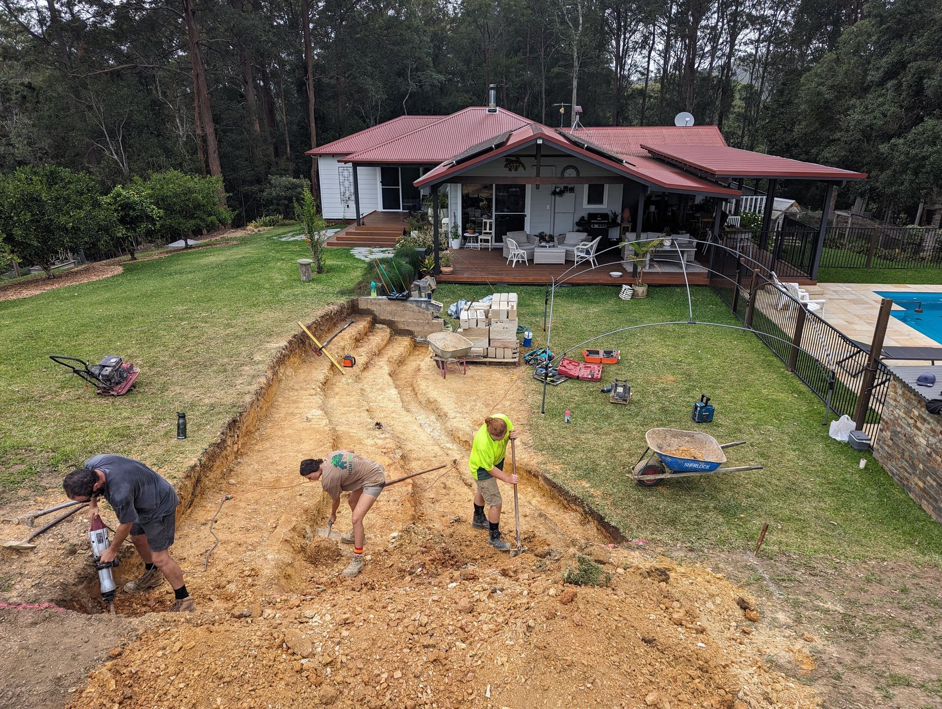 A group of people are working on a dirt road in front of a house.