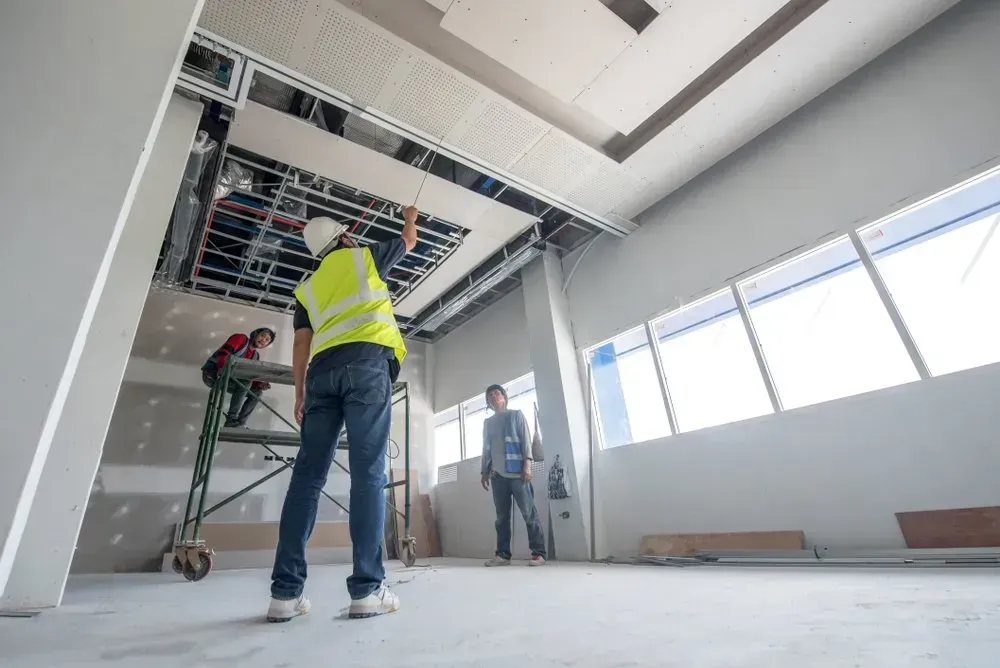 A group of construction workers are working on the ceiling of a building.