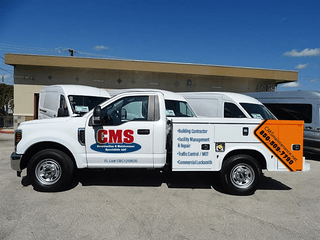 A white truck with cms written on the side is parked in front of a building
