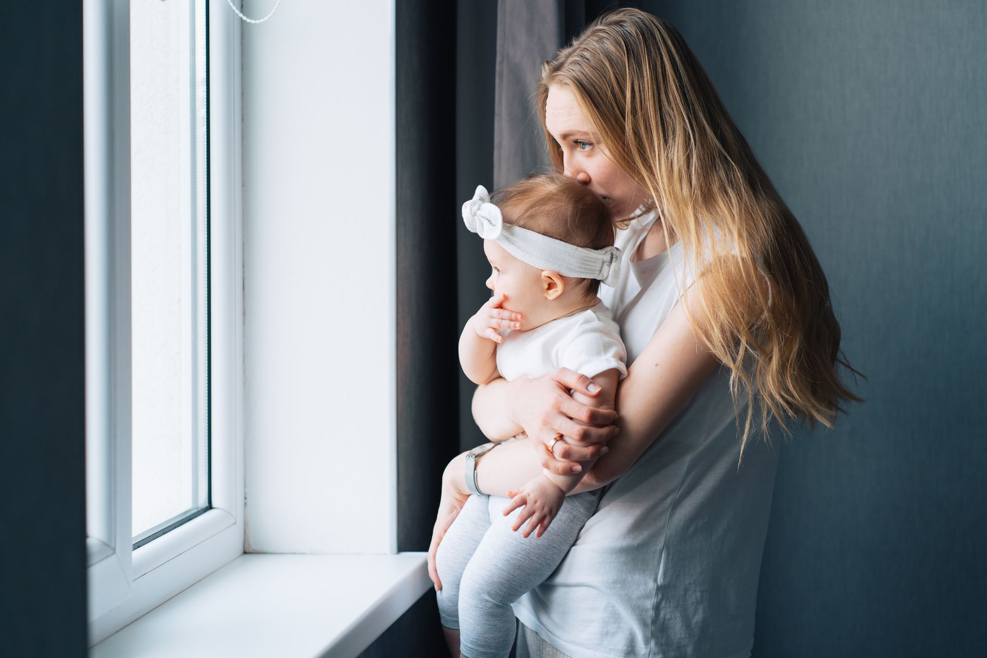 A woman is holding and kissing a baby’s head.