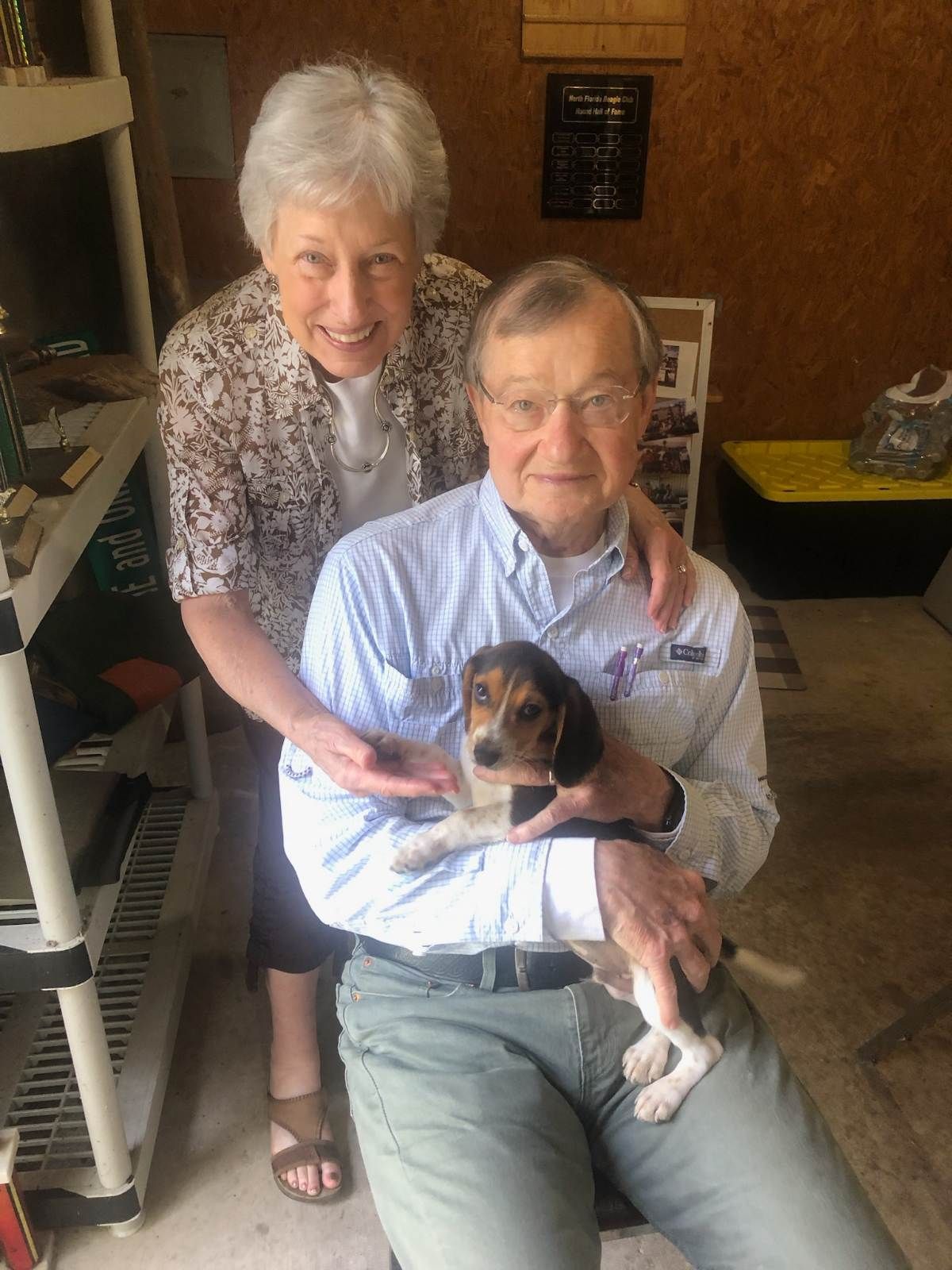 A man and woman are posing for a picture with a puppy.