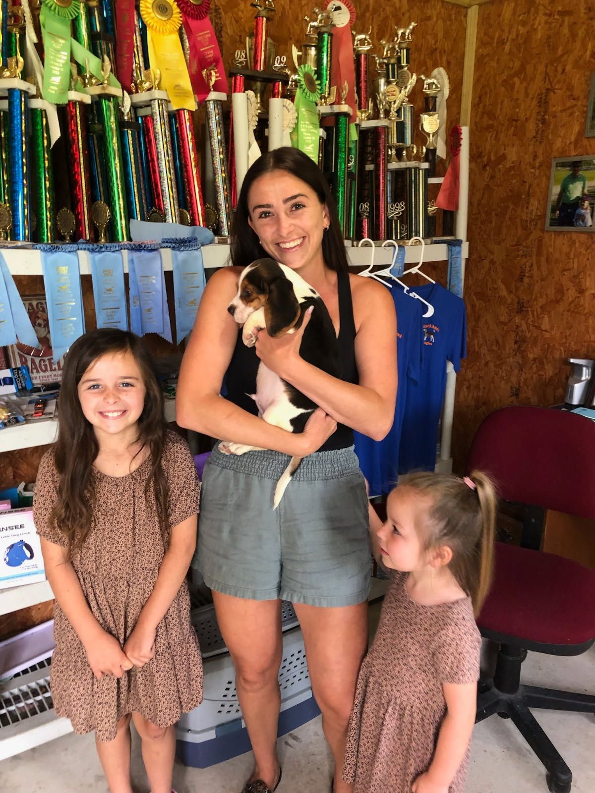 A woman is holding a puppy next to two little girls