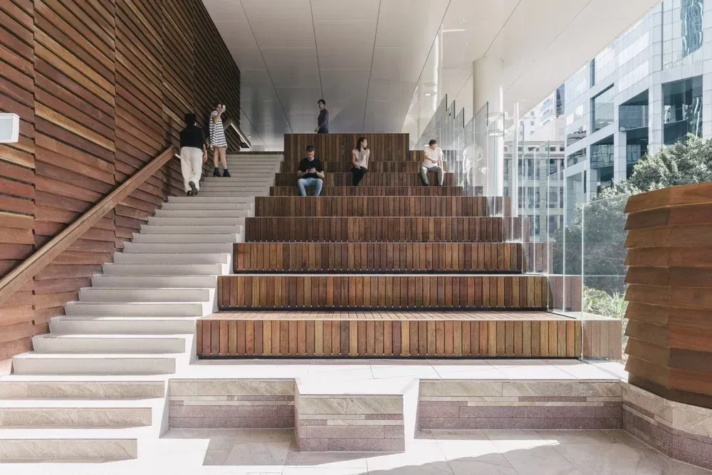 A Group of People Are Sitting on Wooden Steps in A Building — Bootle Timber QLD Pty Ltd in Garbutt, QLD