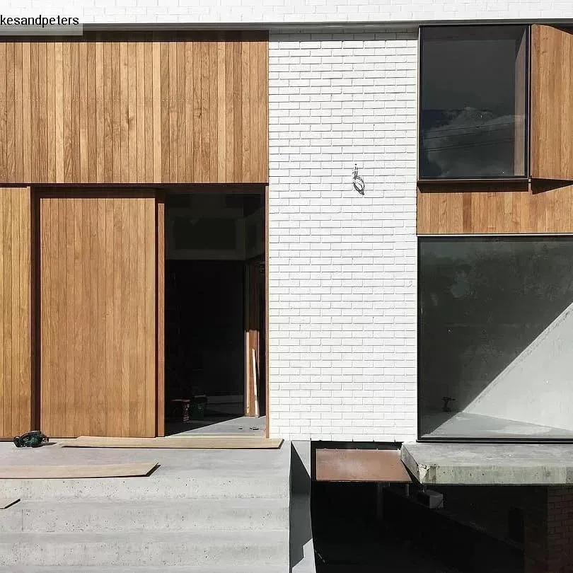 A White Brick Building with A Wooden Door and Windows — Bootle Timber QLD Pty Ltd in Garbutt, QLD