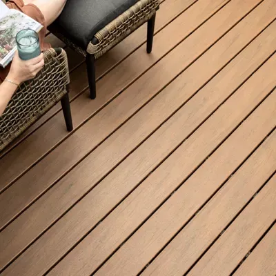 A Person Is Sitting on A Wicker Chair on A Wooden Deck Holding a Glass of Water — Bootle Timber QLD Pty Ltd in Garbutt, QLD