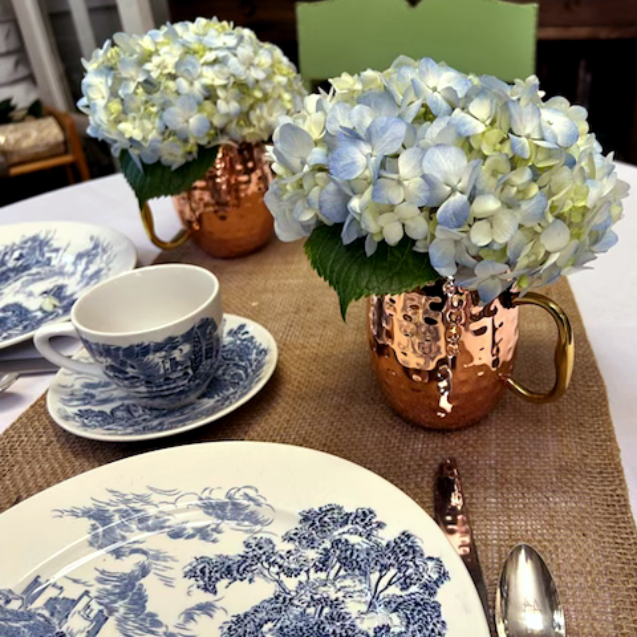 A table with plates cups and vases of flowers