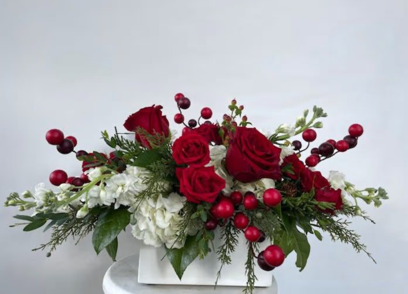 Red roses and berries in white floral arrangement.
