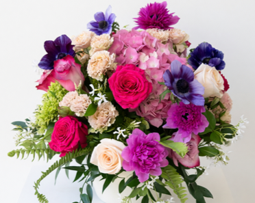 Luxurious bouquet of vibrant garden flowers with green foliage on a white background