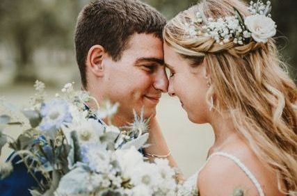 A bride and groom are touching their foreheads and looking at each other.